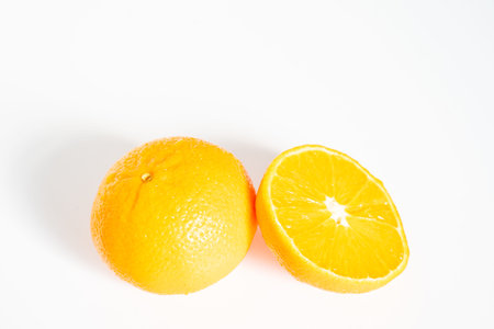 A whole orange and a half against a plain white backgroundの写真素材