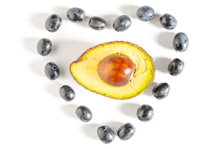 Half an avocado in the center of some black grapes in the shape of a heart