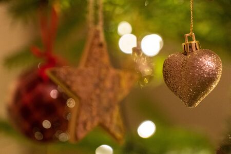 A glittery heart shaped Christmas Tree Decoration hanging from a treeの写真素材
