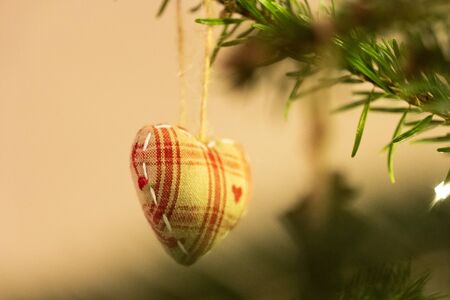 A fabric heart shaped Christmas Tree Decoration hanging from a treeの写真素材