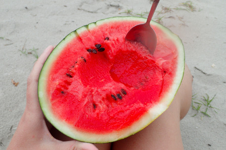 A piece of red watermelon on the beachの写真素材