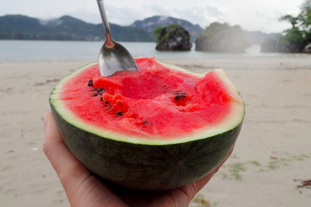 A piece of red watermelon on the beachの写真素材
