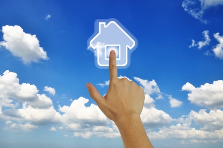 Hand pressing home symbol  on   blue skyの写真素材