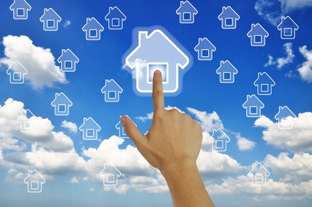 Hand pressing home symbol  on  grassland  blue skyの写真素材