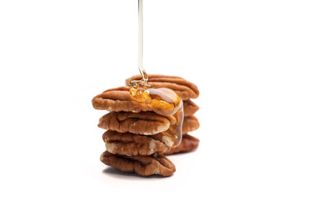 Pouring honey on Fresh Pecans isolated on white