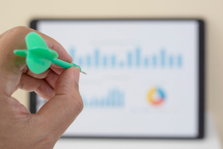 Hand holding arrow aim to target chart on wall