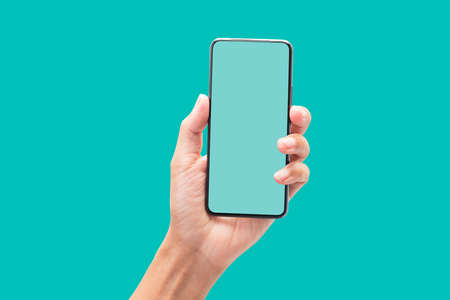 Hand holding smartphone with blank screen on blue green backgroundの写真素材
