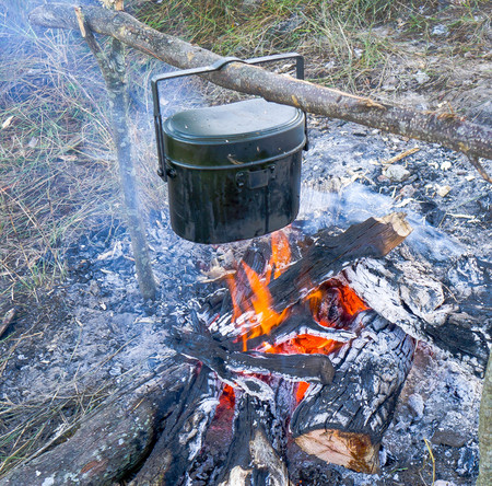Preparing food and hot pot on campfire in wild campingの写真素材