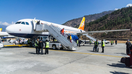 PARO, BHUTAN - March 2, 2016: People arriving at Paro airport, Bhutan with druk air, the "dragon airline", the only airline that is aloud to land in Bhutan. In the background are the mountains.のeditorial素材