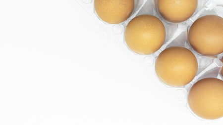brown eggs in a carton transparent package on white background.の写真素材