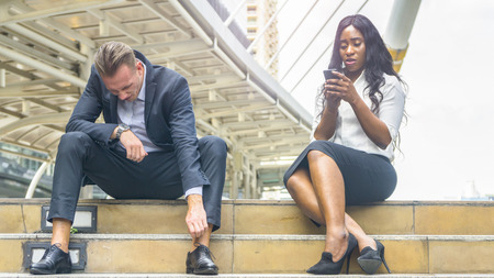 group of three people multi nationality Business workers man and woman sit on the stair relax in the morning with the city space backgroundの写真素材