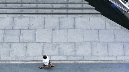 the top aerial view of the man with white shirt walk over grey textured pedestrian street and concrete grey pavement backgroundの写真素材