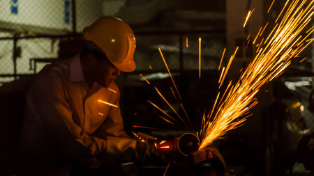 the worker uses cutting machine to cut metal, focus on flash light line of sharp spark,in low Light
