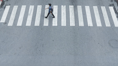 In the side view of man walk fast across the sign of crossroad in the city street.の写真素材