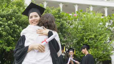 girl student with the Graduation gowns and hat hug the parent in congratulation ceremony.の写真素材