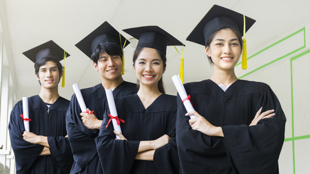 the people students man and woman with black graduation gowns hold the diploma and stand together. With the feeling of happy and graceful.の写真素材