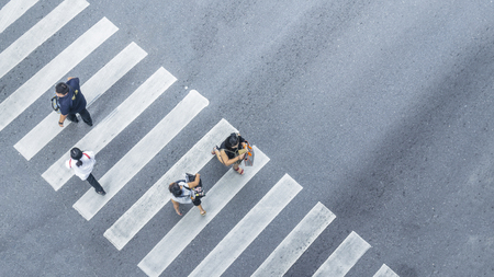 From the top view of people walk on street pedestrian crossroad in the city street with the motorcycle drives pass road ,bird eye view.