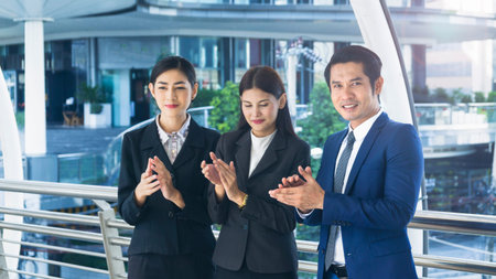 group of smart people of man and woman stand and clap hands in the feeling of happy and success at the outdoor pedestrian walk wayの写真素材