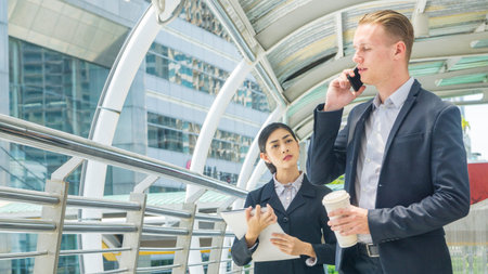 business people lady and caucasian man talk with smart phone and walk on pedestrian walk way
