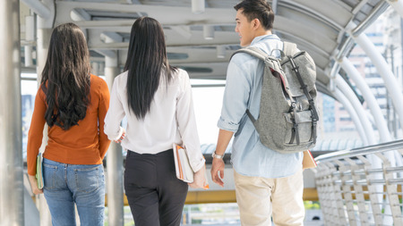 back of teen people and business woman walk and talk at  outdoor publicの写真素材