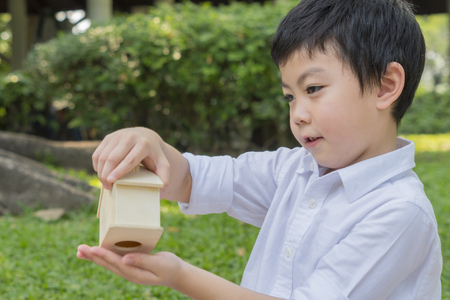 boy plays piggy bank toy house in picnic garden parkの写真素材