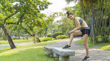 Asian cute healthy fit and firm slim teen lady warm up before workout for weight training or running at outdoor garden parkの写真素材