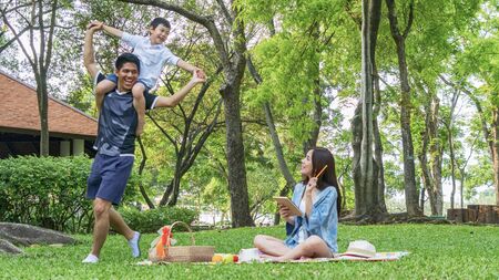 Family Picnic at garden park Outdoors Together Relaxation Concept with kid rides on the father's neck.の写真素材