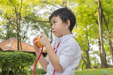 boy use stethoscopes and play with fruit orange symbolの写真素材
