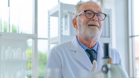 Senior professor male researcher think with face concentration about lab testing science. with interior white lab and equipments on desk.の写真素材