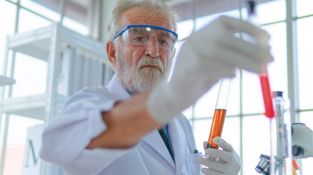Senior professor male researcher tests a chemical liquid tube with face concentration about lab testing science. with interior white lab and equipments on desk.の写真素材