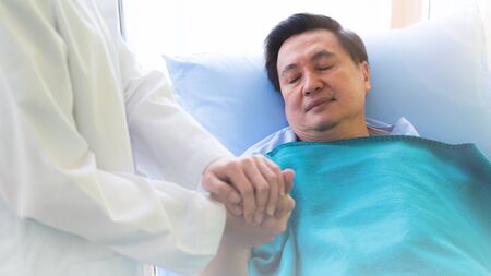 Sick elderly Asian senior man resting in hospital bed with the doctor suggestion near the bed.の写真素材