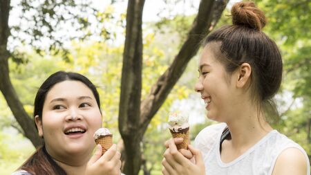 two people fat and cute girl eat ice cream with feeling deliciousの写真素材