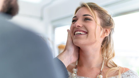 Portrait of woman in wedding dress with happy smile with his boyfriend's hand, stroking her head in...