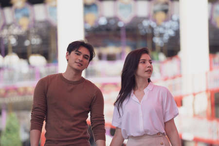 A couple in love of young funny and happy woman and man walking or running at amusement park background. Human emotions, youth, love and lifestyle concept.の写真素材
