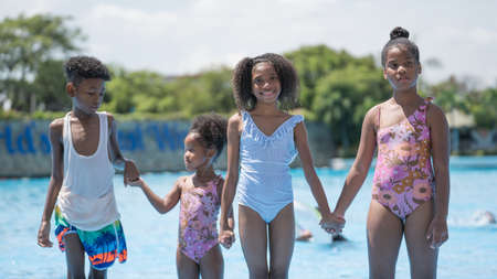 African girls and boy standing and playing in swimming water pool at amusement park.  Concept kid are expressing pure joy and excitementの写真素材