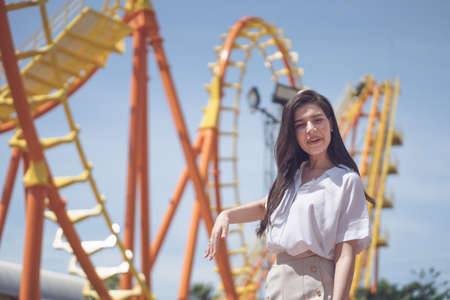 tourist young woman standing in feeling happy at front of 
Roller coaster in amusement park. Concept happy life in the vacation in summer day.の写真素材