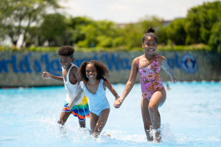 African kid girls and boy running to swimming water pool at amusement park.  Concept kid are expressing pure joy and excitementの写真素材