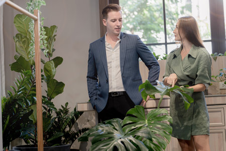 Portrait of happy businessman and woman check and treat green trees plant leaves at indoor building garden. Concept office space with biophilia nature.の写真素材