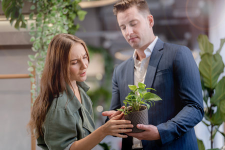 Portrait of happy businessman and woman hold and treat plat pot green trees plant leaves at indoor building garden. Concept office space with biophilia nature.の写真素材