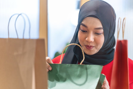 happy face muslim woman in red dress checking shopping bags. Concept people activity in shopping festival season christmas and new year.の写真素材