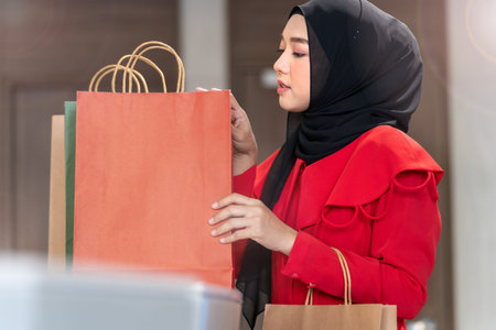 happy face muslim woman in red dress checking shopping bags. Concept people activity in shopping festival season christmas and new year.の写真素材