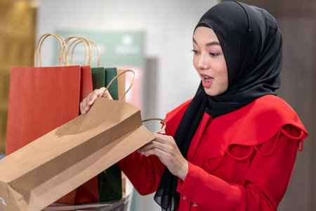 happy face muslim woman in red dress checking shopping bags. Concept people activity in shopping festival season christmas and new year.の写真素材