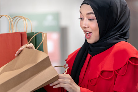happy face muslim woman in red dress checking shopping bags. Concept people activity in shopping festival season christmas and new year.の写真素材
