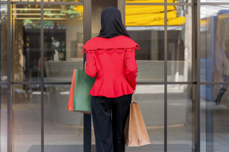 woman in red dress holding shopping bag and walking to shop building. Concept people activity in shopping festival season christmas and new year.の写真素材