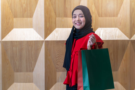happy face muslim woman in red dress holding shopping bag. Concept people activity in shopping festival season christmas and new year.の写真素材