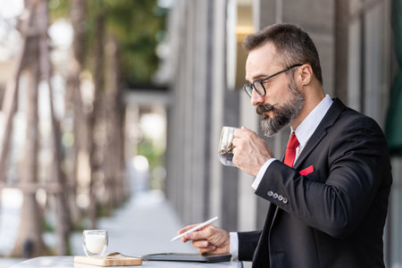 senior man in smart business suit thinking and sitting in outdoor coffee table.の写真素材
