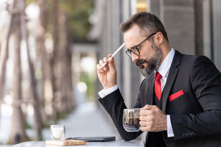 senior man in smart business suit thinking and sitting in outdoor coffee table.の写真素材