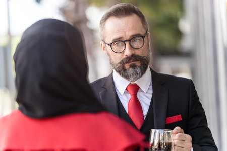 senior man in smart business suit talking to people and sitting in outdoor coffee table.の写真素材