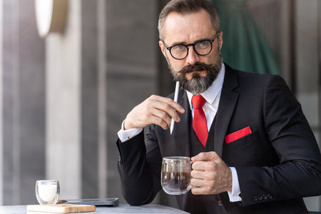 senior man in smart business suit thinking and sitting in outdoor coffee table.の写真素材