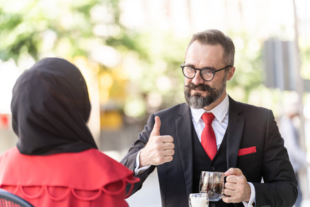 senior man in smart business suit talking to people and sitting in outdoor coffee table.の写真素材